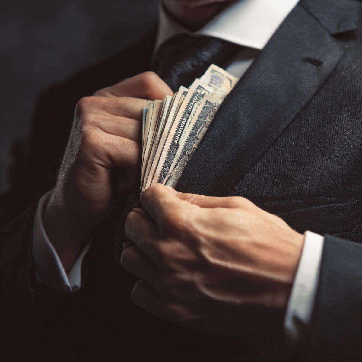 Corporate extortion targeting modern businesses - business professional in suit holding cash money representing financial demands and massive monetary gain sought by sophisticated criminals targeting corporate vulnerabilities