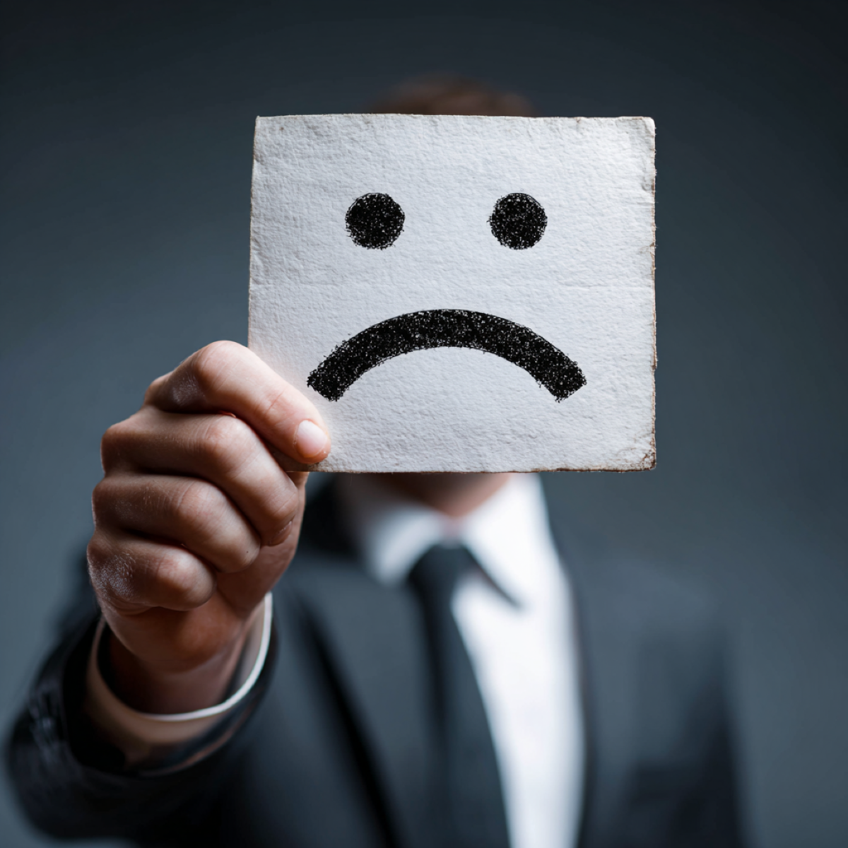 Negative content gets worse over time - business professional holding sad face emoji card representing deteriorating reputation from unaddressed negative online content